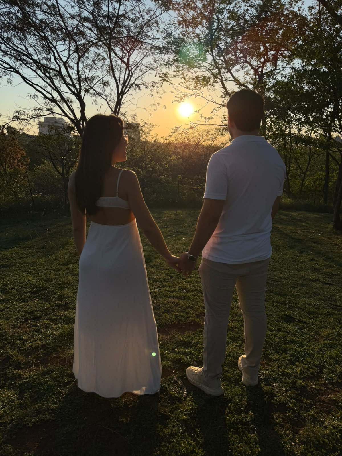 Carolina e João Vitor de mãos dadas em um campo ao pôr do sol